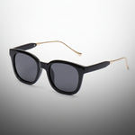 Black sunglasses with gold accents on a white background