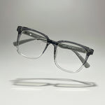 Clear eyeglasses held by a hand against a neutral background